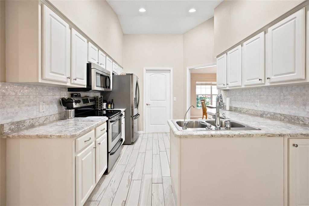 A kitchen with white cabinets, stainless steel appliances, and light-colored countertops and flooring — 500 NE 52ND COURT, OCALA, FL