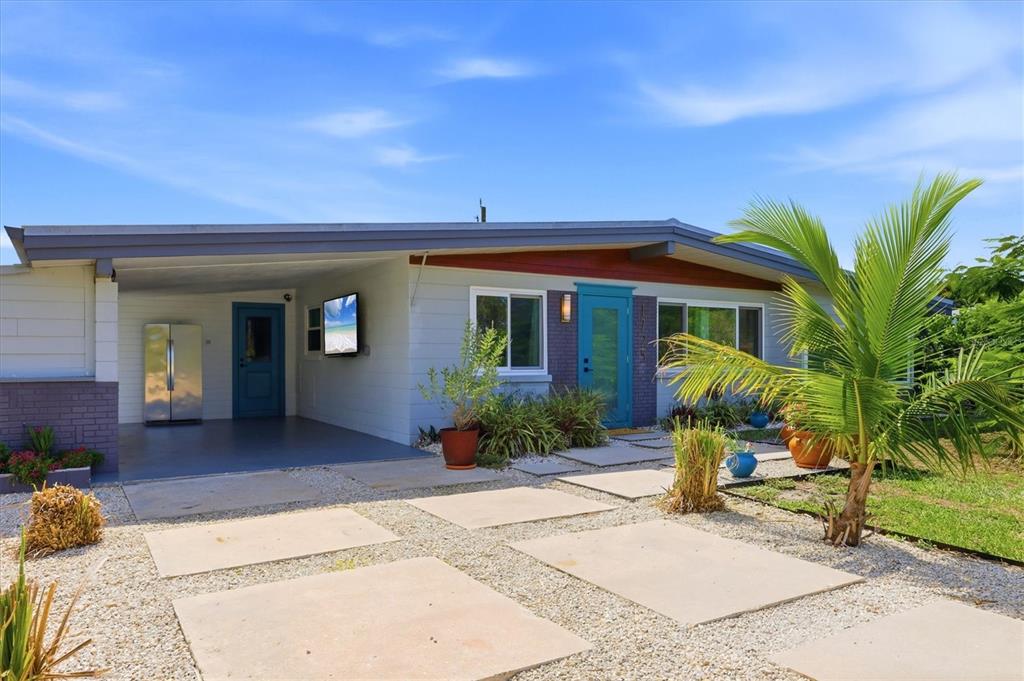 A single-story house with a carport, blue front door, and a gravel driveway with pavers — 1725 MEL O DE LANE, ENGLEWOOD, FL