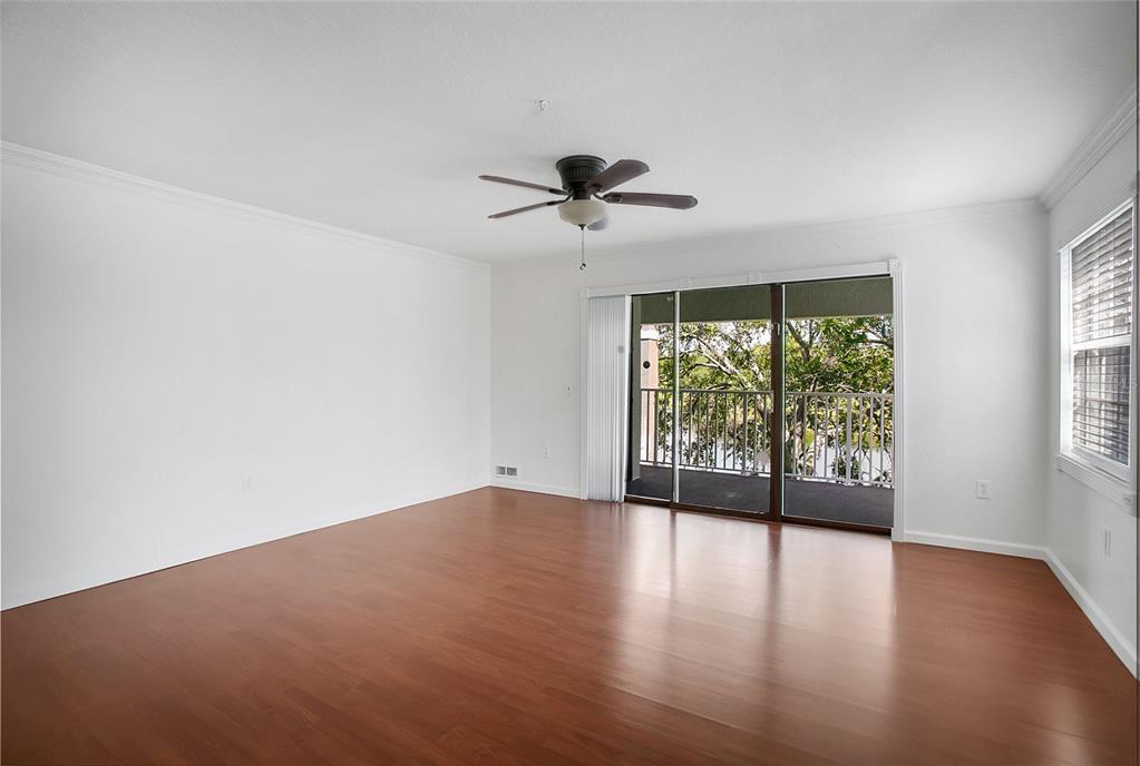 An empty room features white walls, dark wood-look flooring, a ceiling fan, and a balcony — 13815 FAIRWAY ISLAND DRIVE UNIT 1328, ORLANDO, FL
