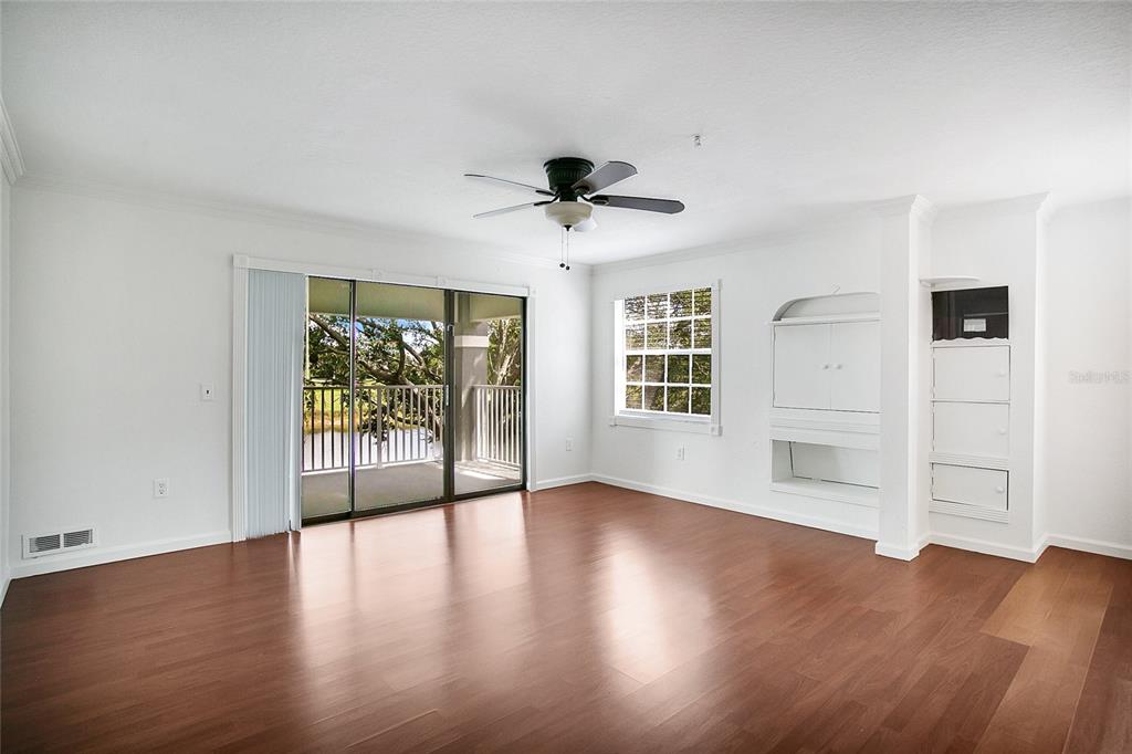 A living room with wood-look flooring, a ceiling fan, built-in shelving, and a sliding glass door — 13815 FAIRWAY ISLAND DRIVE UNIT 1328, ORLANDO, FL