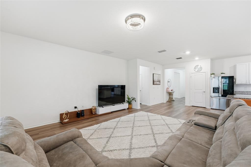 A living room features a large sectional sofa, a television on a low stand, and flooring — 2081 MALBEC COURT, MINNEOLA, FL