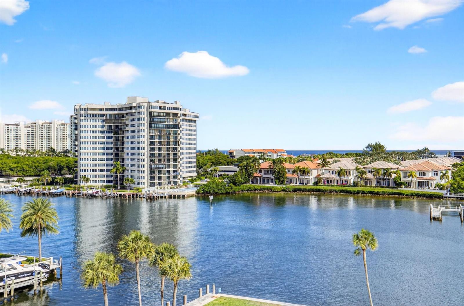 A view of a waterfront high-rise apartment building and nearby houses across a calm bay — 899 Jeffery Street # 710, Boca Raton FL 33487, BOCA RATON, FL