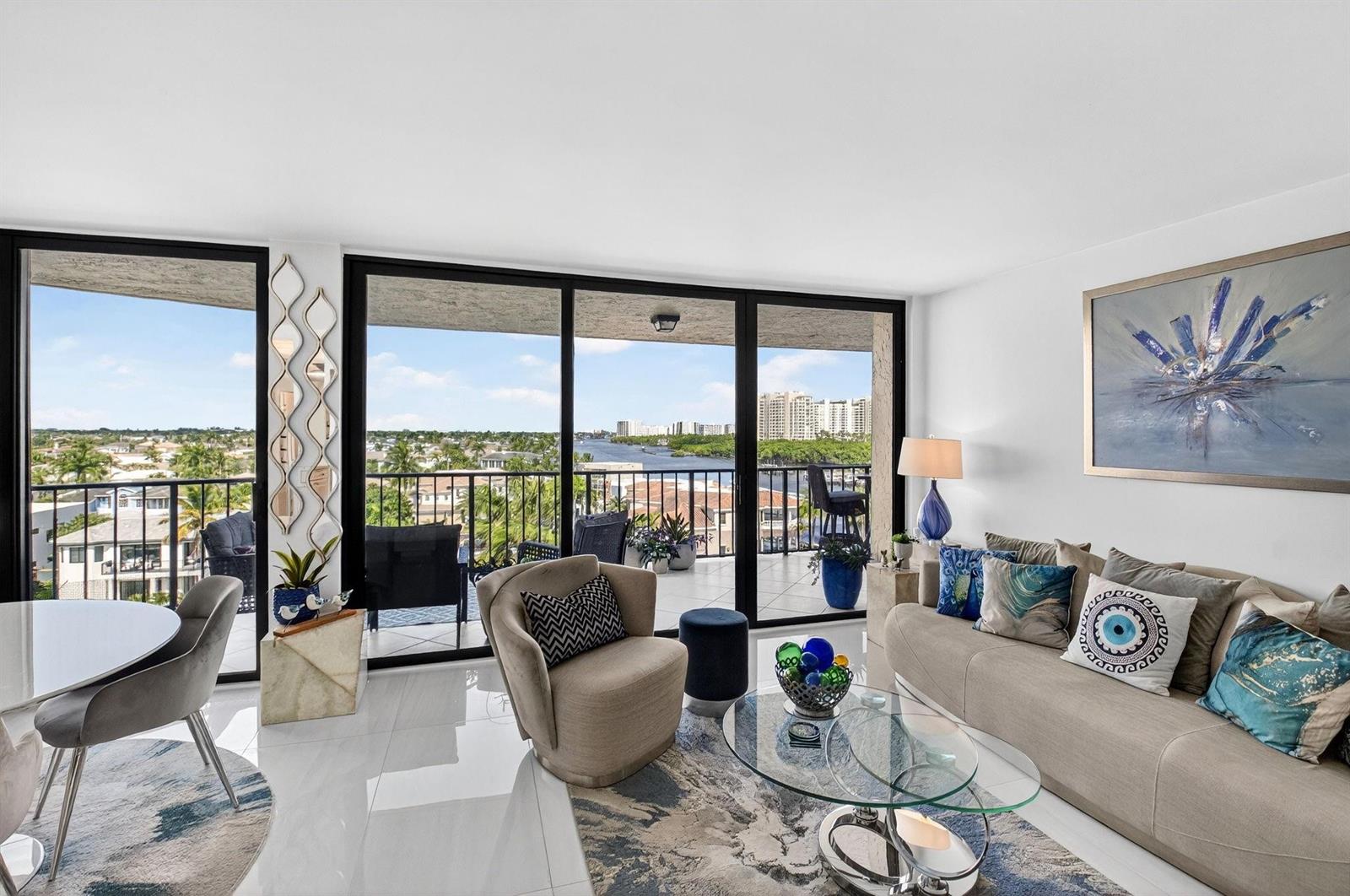 A living room with a glass coffee table, beige sofa, and balcony overlooking a waterway — 899 Jeffery Street # 710, Boca Raton FL 33487, BOCA RATON, FL