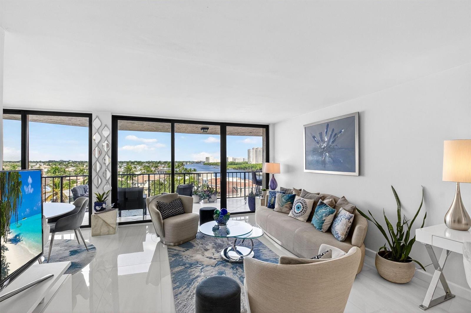 A bright living room features white tile floors, a neutral sofa, and a balcony view — 899 Jeffery Street # 710, Boca Raton FL 33487, BOCA RATON, FL