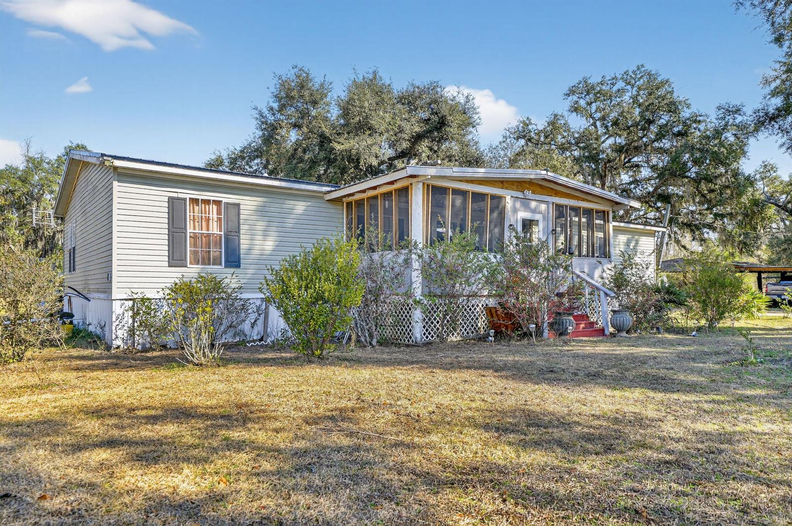 A single-story manufactured home features a screened-in front porch and light-colored siding — 7638 Sundown Creek Road, FL 32331, FL