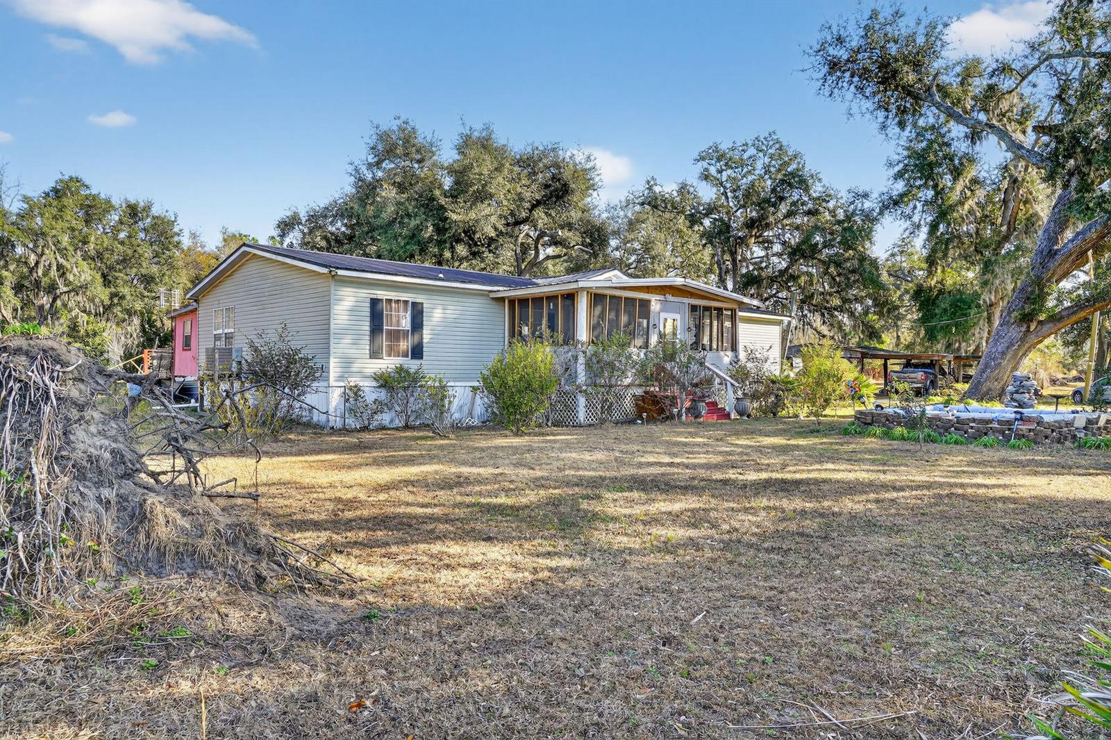 A single-story manufactured home with a screened-in front porch sits on a grassy lot — 7638 Sundown Creek Road, FL 32331, FL