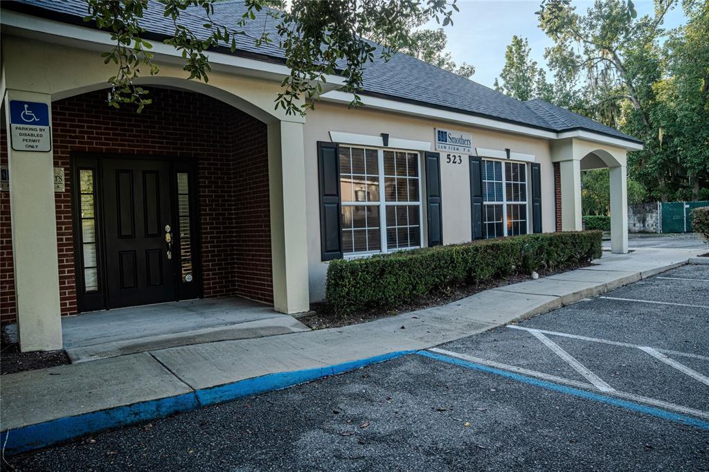 The exterior of a single-story commercial building features a brick entrance, tan siding, and windows — 523 WEKIVA COMMONS CIRCLE UNIT 4, APOPKA, FL