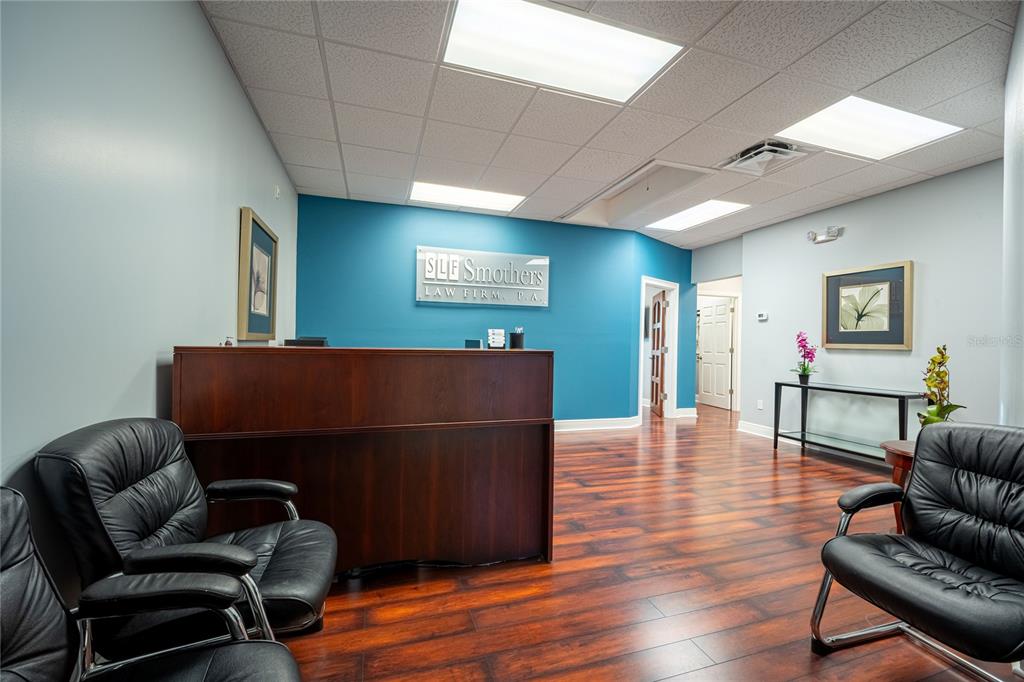 A law firm reception area features a dark wood desk, black leather chairs, and wood flooring — 523 WEKIVA COMMONS CIRCLE UNIT 4, APOPKA, FL