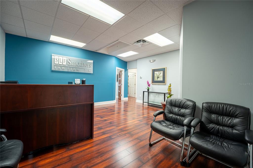 A law firm reception area features a dark wood desk, teal accent wall, and chairs — 523 WEKIVA COMMONS CIRCLE UNIT 4, APOPKA, FL