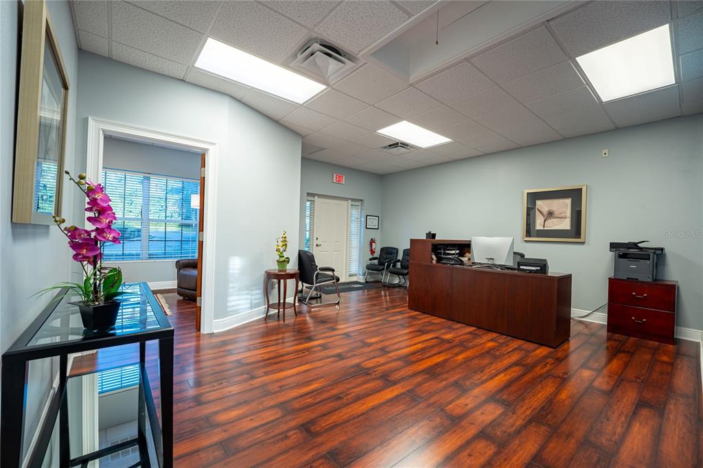 A reception area features wood-look flooring, a dark wood desk, and a drop ceiling — 523 WEKIVA COMMONS CIRCLE UNIT 4, APOPKA, FL