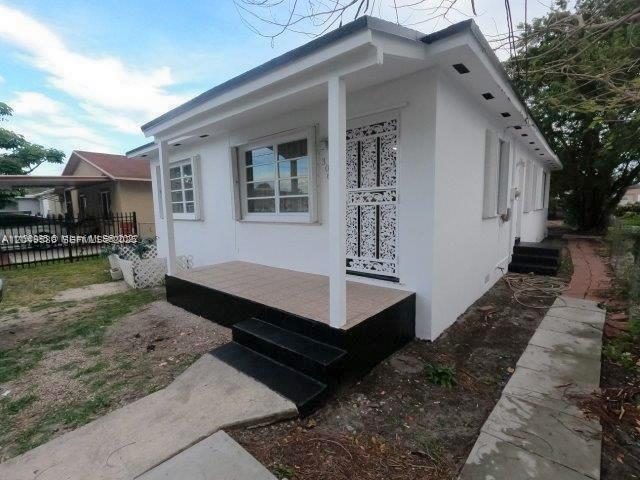 A white, single-story house features a front porch with black steps and a decorative door — 3062 NW 60th St, Miami FL 33142, MIAMI, FL