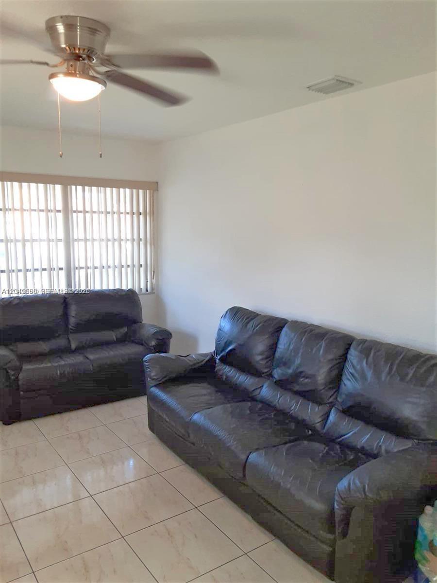 A living room features two black leather sofas, tile flooring, and a ceiling fan — 3062 NW 60th St, Miami FL 33142, MIAMI, FL