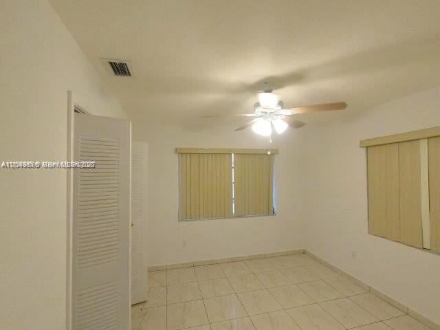An empty bedroom with white walls, tile flooring, a ceiling fan, and louvered closet doors — 3062 NW 60th St, Miami FL 33142, MIAMI, FL