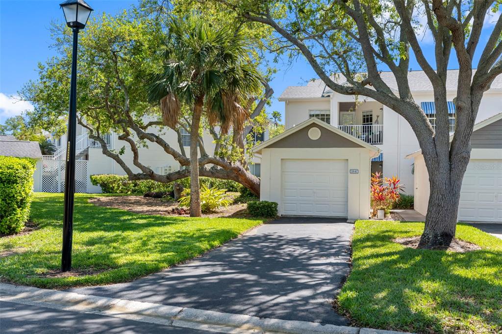 A single-story garage with a driveway sits in front of a multi-story residential building — 11351 SHIPWATCH LANE UNIT 1841, LARGO, FL