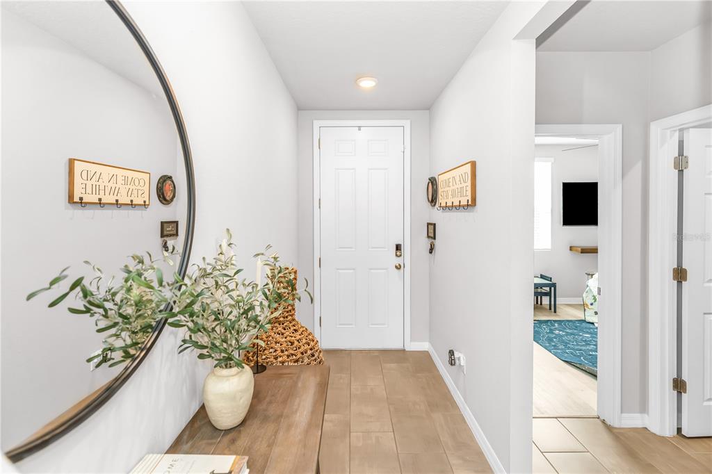 A bright entryway features a wooden console table, a large round mirror, and tile flooring — 224 TOWNS CIRCLE, HAINES CITY, FL