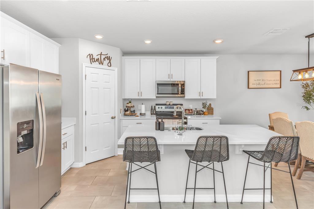 A modern kitchen features white cabinets, a large island with three stools, and stainless appliances — 224 TOWNS CIRCLE, HAINES CITY, FL