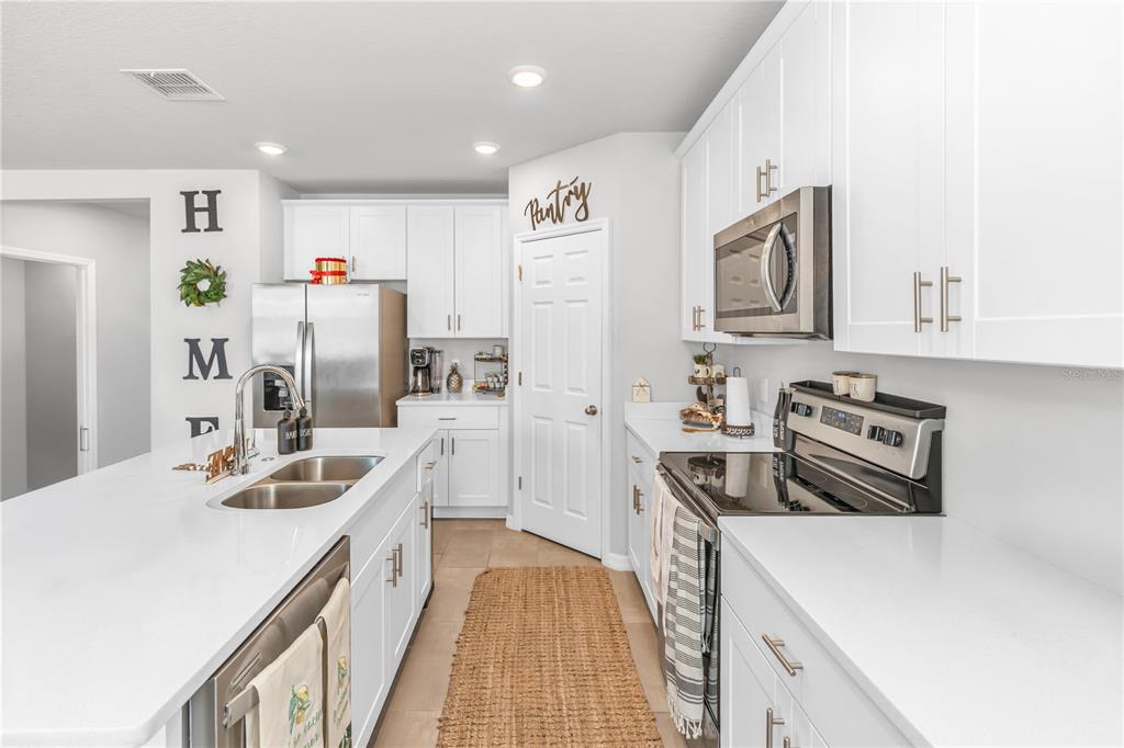 A modern kitchen features white cabinetry, stainless steel appliances, a center island, and tile flooring — 224 TOWNS CIRCLE, HAINES CITY, FL