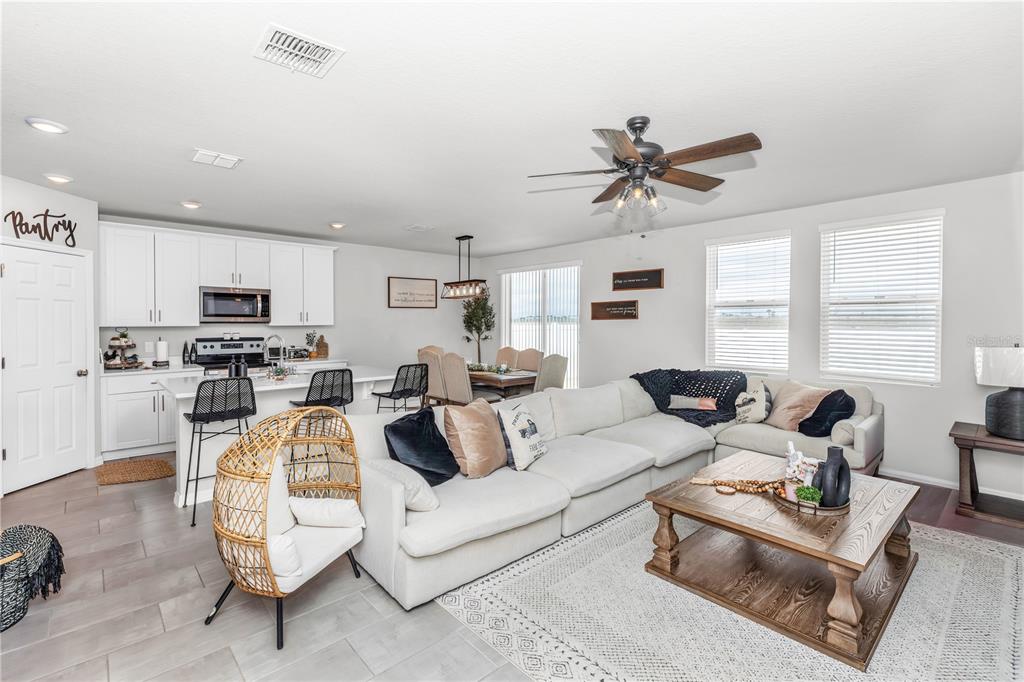 An open-concept living room and kitchen feature white cabinetry, a large sectional, and tile flooring — 224 TOWNS CIRCLE, HAINES CITY, FL