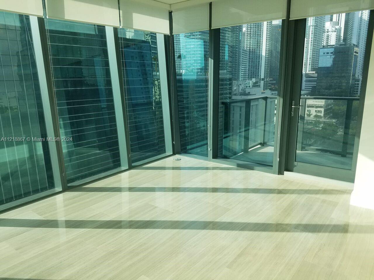 An empty room features floor-to-ceiling windows, light-colored tile flooring, and a balcony overlooking city buildings — 1451 Brickell Ave # 1206, Miami FL 33131, MIAMI, FL