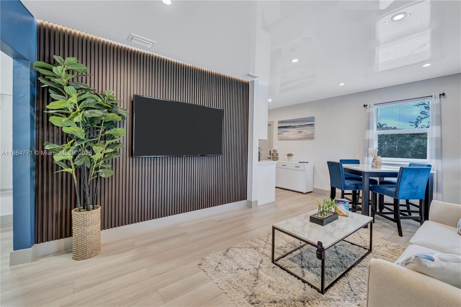 A living room features a slatted wood accent wall, a television, and a dining area — 1390 NE 150th St, Miami FL 33161, MIAMI, FL