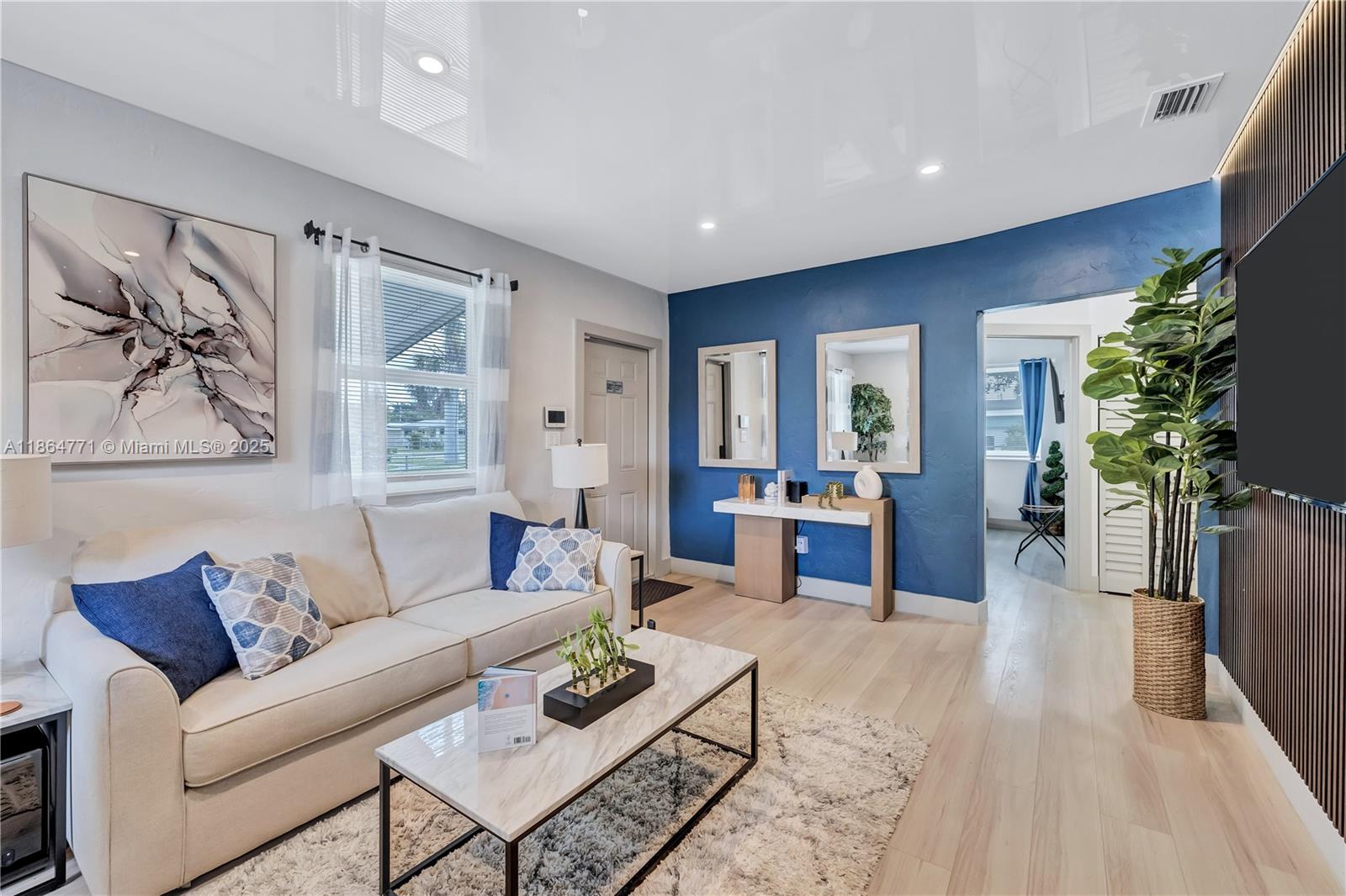 A living room features a white sofa, a marble coffee table, and a blue accent wall — 1390 NE 150th St, Miami FL 33161, MIAMI, FL