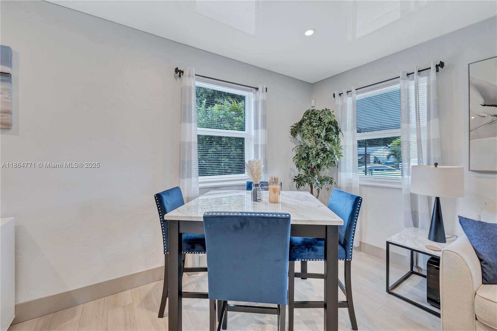 A dining area features a marble-topped table, four blue velvet chairs, and two windows — 1390 NE 150th St, Miami FL 33161, MIAMI, FL
