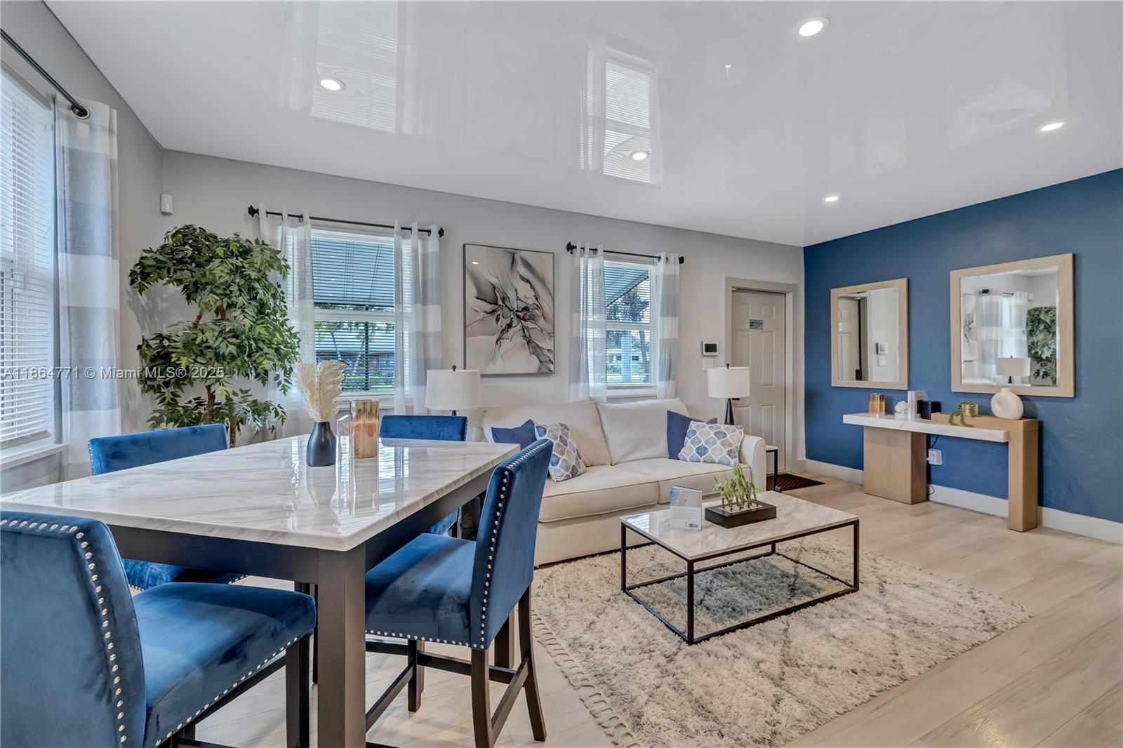A living and dining area features a marble table, blue velvet chairs, and a blue accent wall — 1390 NE 150th St, Miami FL 33161, MIAMI, FL