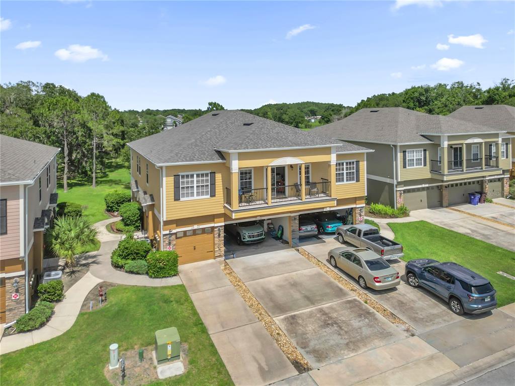 An aerial view of a yellow two-story house with a ground-level garage and driveway — 2309 BETSY ROSS LANE UNIT 2309, ST CLOUD, FL