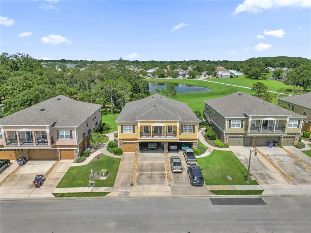 An aerial view shows three multi-story residential buildings with garages facing a street and pond — 2309 BETSY ROSS LANE UNIT 2309, ST CLOUD, FL