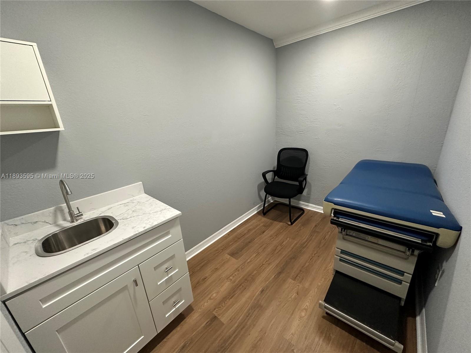 An office room features gray walls, wood-look flooring, a pass-through window, and two black chairs — 7070 Taft St, Hollywood FL 33024, HOLLYWOOD, FL