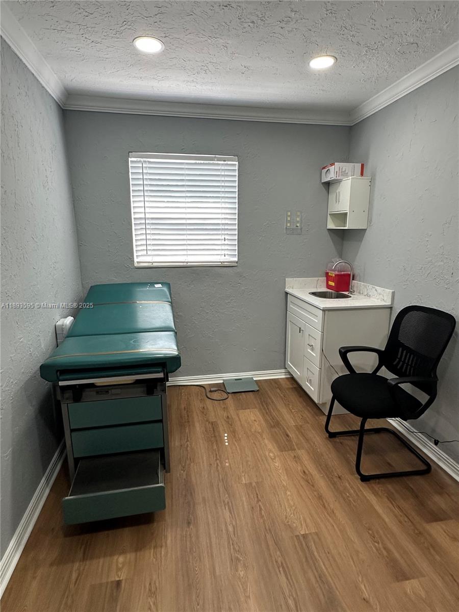 A small medical examination room features a sink, a black chair, and an exam table — 7070 Taft St, Hollywood FL 33024, HOLLYWOOD, FL
