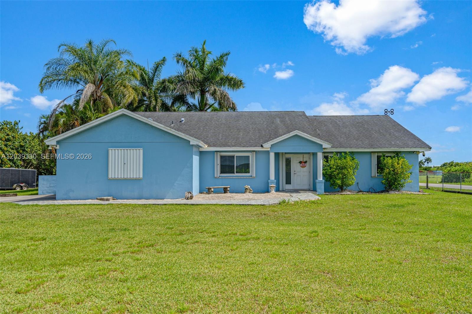 A light blue single-story house features a dark shingled roof and a front lawn — 20950 SW 232nd St, Miami FL 33170, MIAMI, FL