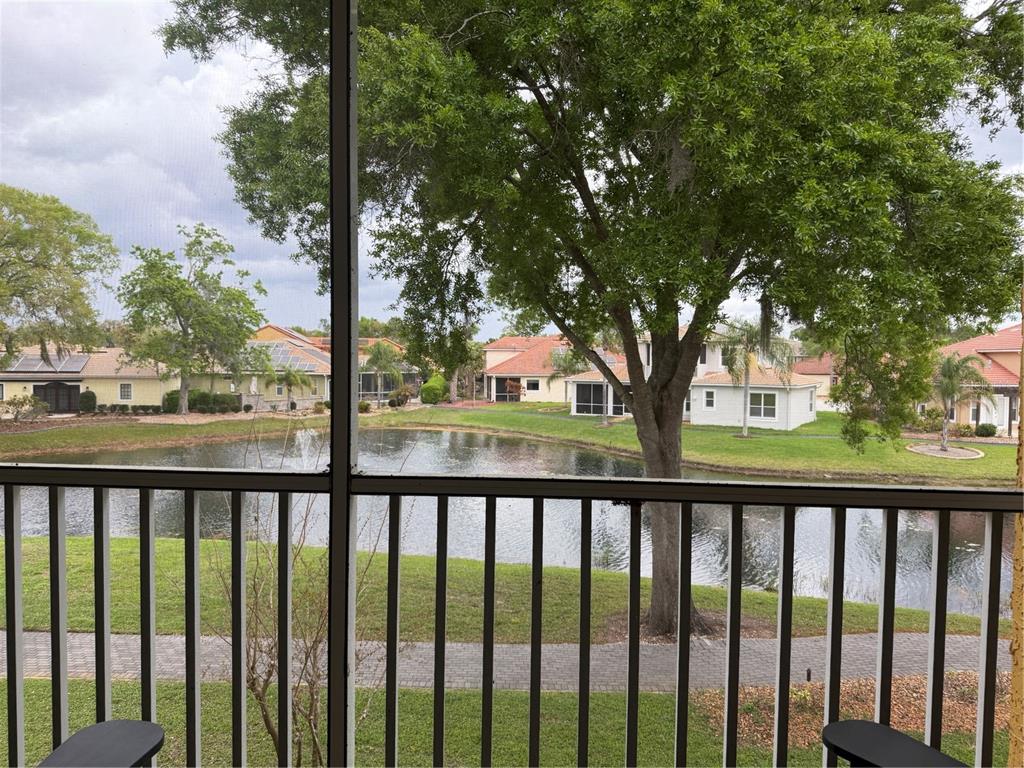 A view of a pond and neighboring houses from a screened-in balcony — 6816 DALI AVENUE UNIT 201, LAND O LAKES, FL