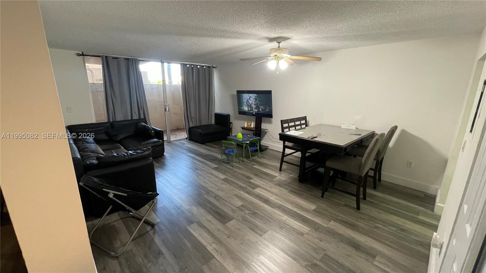 A living room features wood-look flooring, a ceiling fan, and sliding glass doors to a patio — 10801 SW 109th Ct # D108, Miami FL 33176, MIAMI, FL