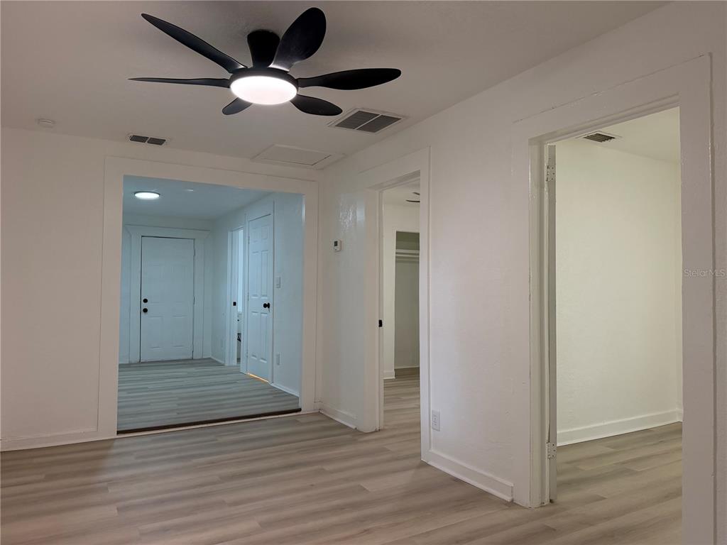 A room with light wood-look flooring, a ceiling fan, and doorways leading to other spaces — 3403 LINDELL AVENUE, TAMPA, FL