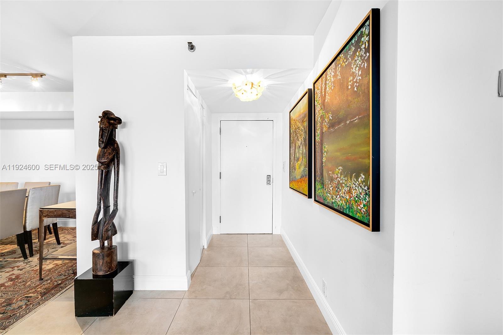 A hallway features tile flooring, a wooden sculpture, and two framed paintings on the wall — 4000 Towerside Ter # 705, Miami FL 33138, MIAMI, FL