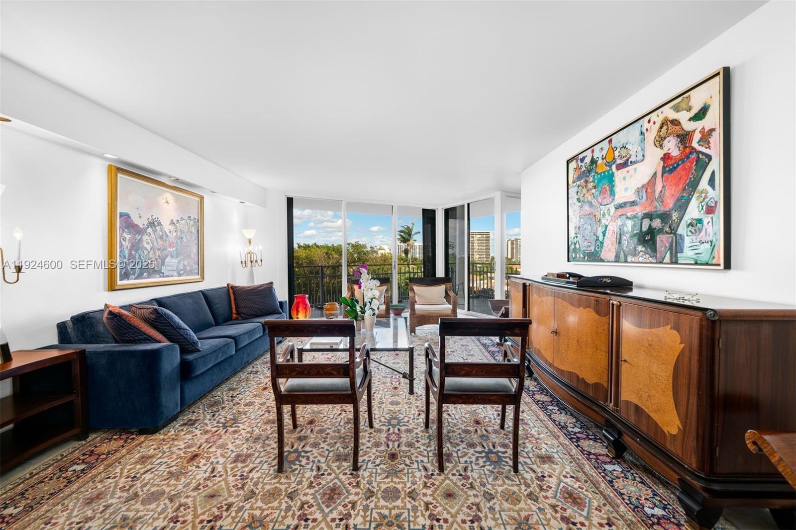 A living room features a blue sofa, wooden sideboard, patterned rug, and floor-to-ceiling windows — 4000 Towerside Ter # 705, Miami FL 33138, MIAMI, FL