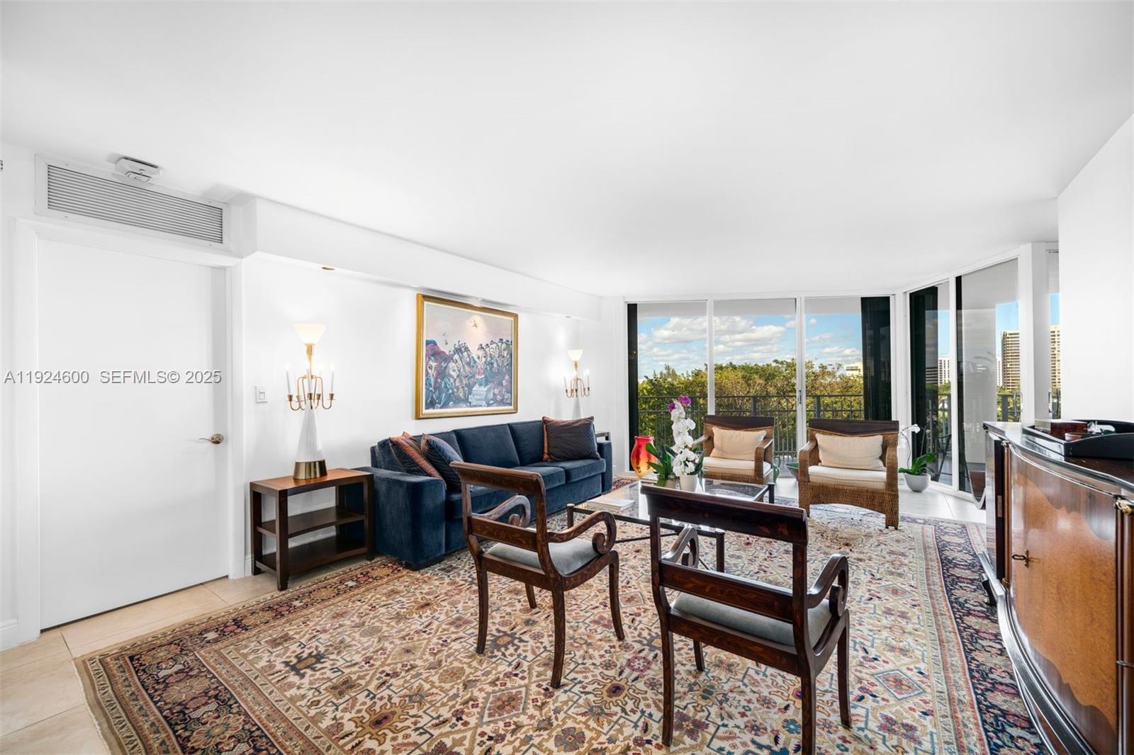 A living room features a blue sofa, two wooden armchairs, and a large patterned rug — 4000 Towerside Ter # 705, Miami FL 33138, MIAMI, FL
