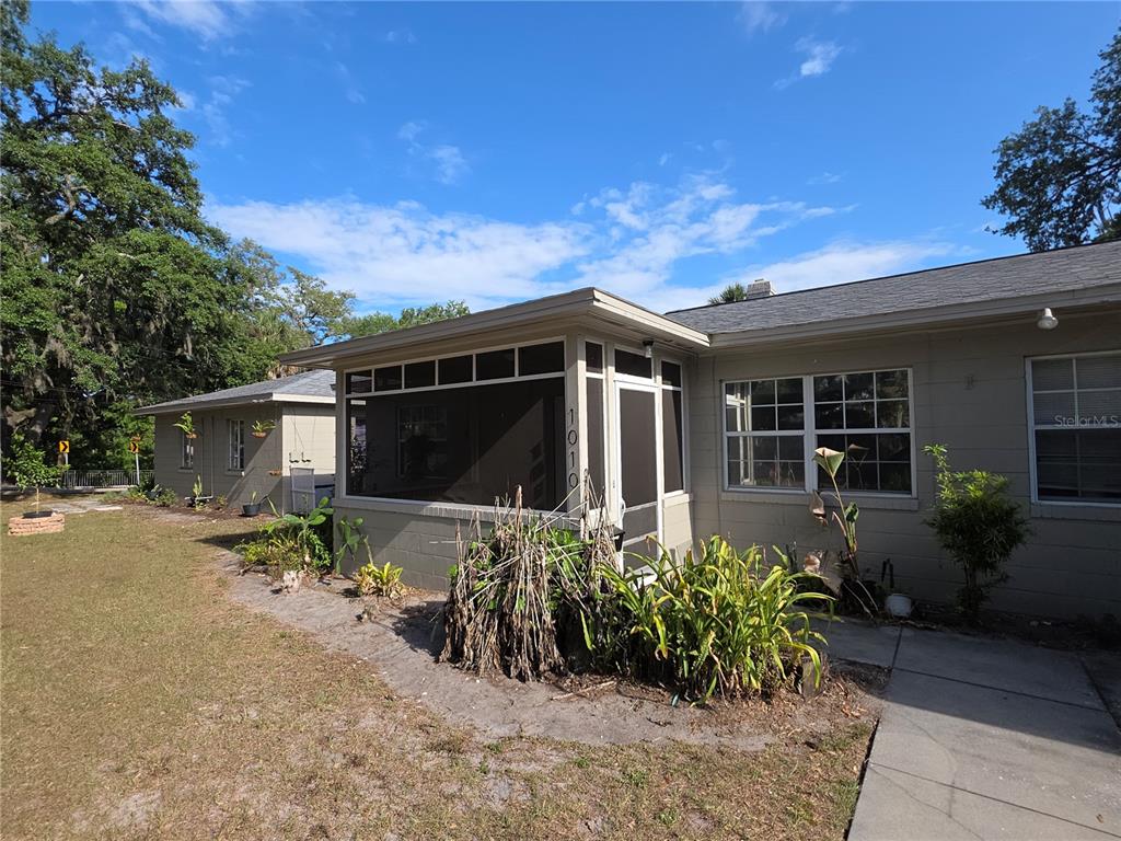 A tan house exterior features a screened-in porch with the address number 1010 displayed vertically — 1010 E CENTRAL BOULEVARD, ORLANDO, FL