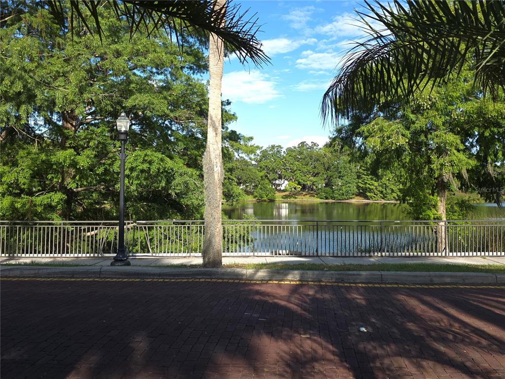 A brick street overlooks a lake bordered by a metal fence and lush green trees — 1010 E CENTRAL BOULEVARD, ORLANDO, FL