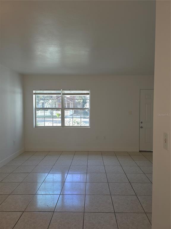 An empty room with white walls, tiled flooring, a window, and a white door — 1010 E CENTRAL BOULEVARD, ORLANDO, FL