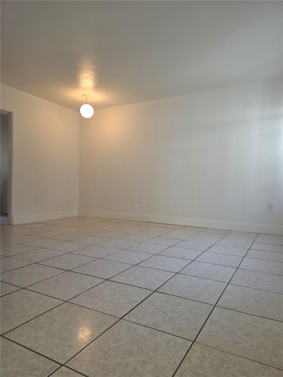 An empty room with white walls, tiled flooring, and a single globe pendant light — 1010 E CENTRAL BOULEVARD, ORLANDO, FL