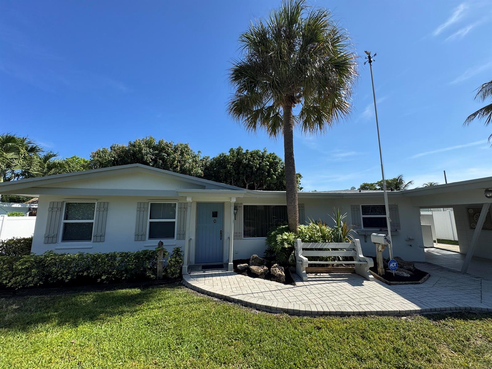 A single-story house with a light blue door, a palm tree, and a paved front patio — 2560 NE 20th Street, Pompano Beach FL 33062, POMPANO BEACH, FL