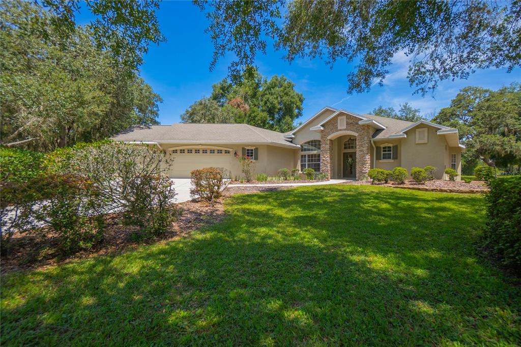 A single-story house with a stone-accented entryway, a three-car garage, and a large front lawn — 9807 E LAKE TAHOE DRIVE, INVERNESS, FL