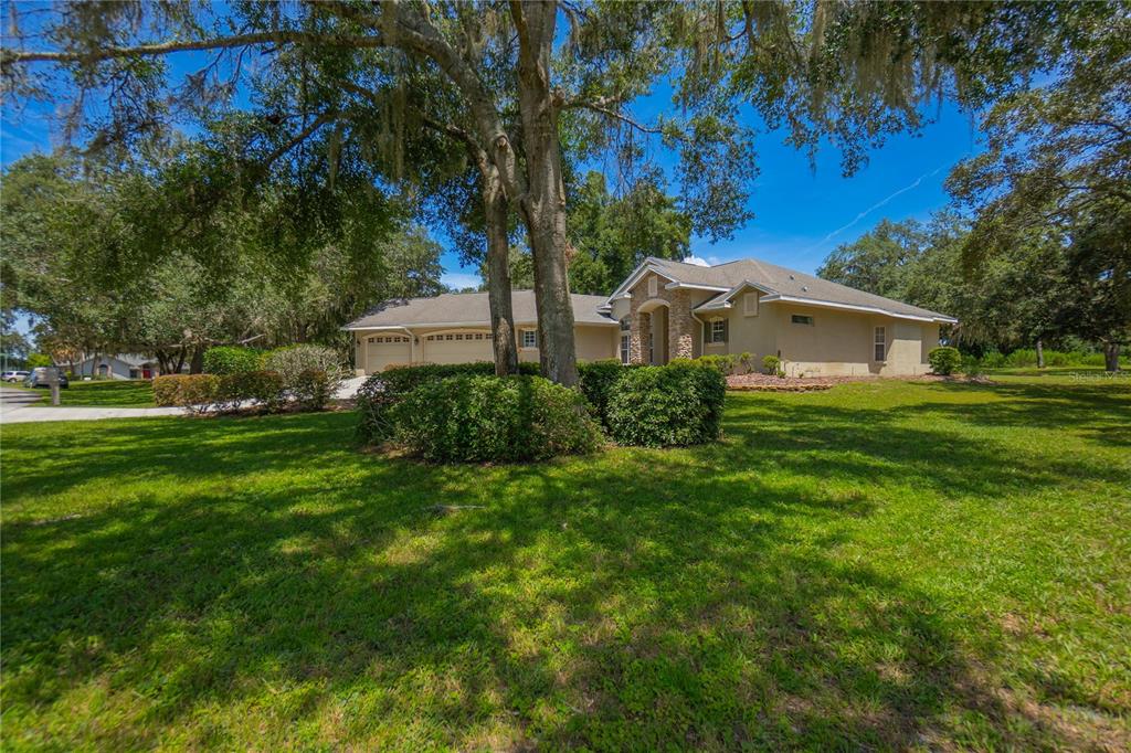 A single-story house with a garage and stone accents sits on a large, grassy lot — 9807 E LAKE TAHOE DRIVE, INVERNESS, FL