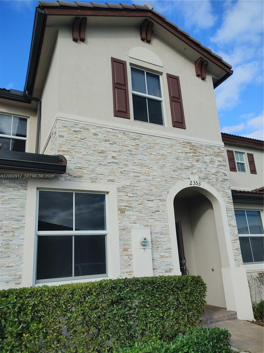 The exterior of a two-story townhouse features stone veneer, brown shutters, and an arched entryway — 2353 NW 122nd Ter # 0, Miami FL 33167, MIAMI, FL