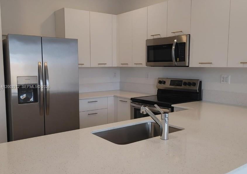 A modern kitchen features white cabinets, stainless steel appliances, and white quartz countertops — 2353 NW 122nd Ter # 0, Miami FL 33167, MIAMI, FL