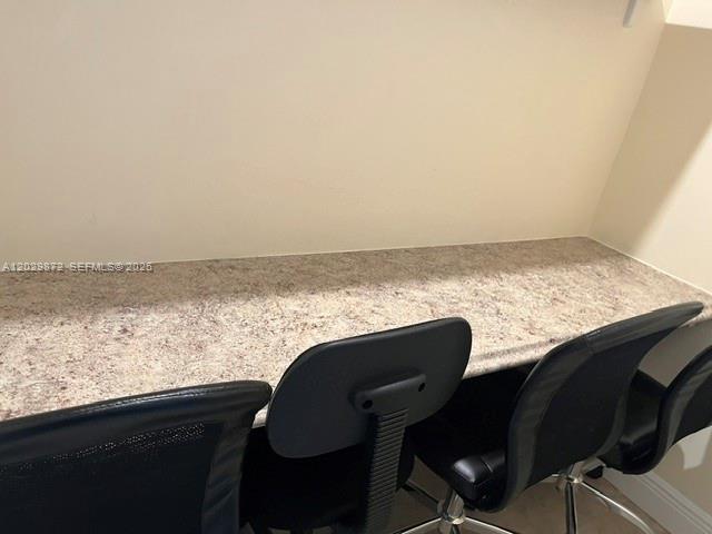A built-in desk with a speckled countertop sits against a plain wall with office chairs — 8260 W Flagler St, Miami FL 33144, MIAMI, FL
