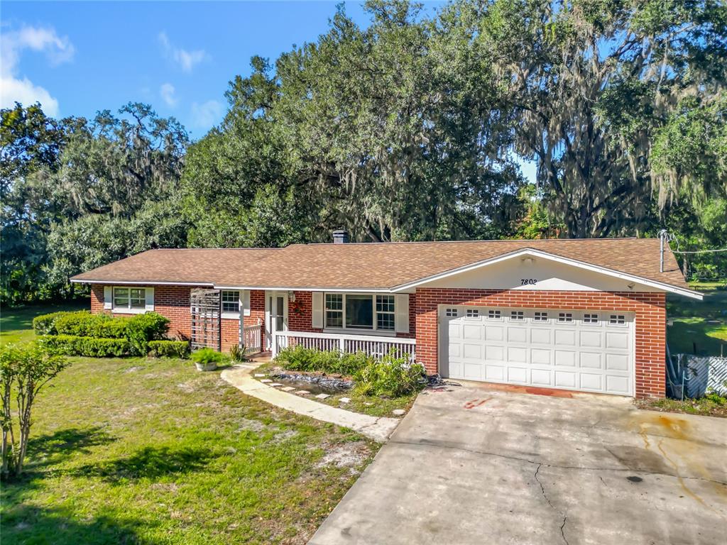 A single-story brick house with a white garage door and a front porch — 7802 MIZELL STREET, COLEMAN, FL