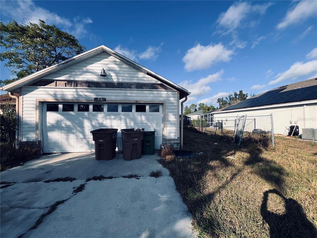 A detached garage with white siding and a concrete driveway sits next to a house — 2247 SW 4TH STREET, CAPE CORAL, FL